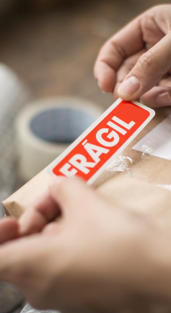 0032hands holding a red fragile sticker to stick it on 2023 11 27 05 11 56 utc